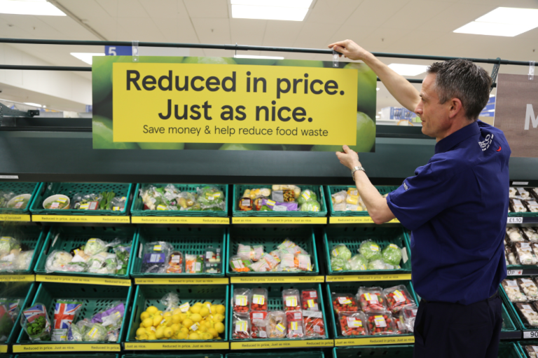 Worker in tesco putting up a sign