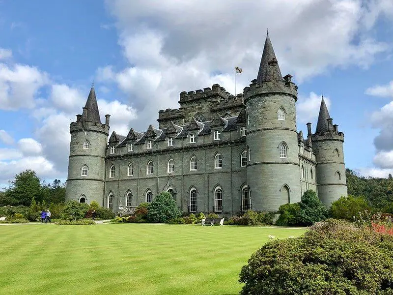 Inveraray Castle with a bright blue sky and green garden.